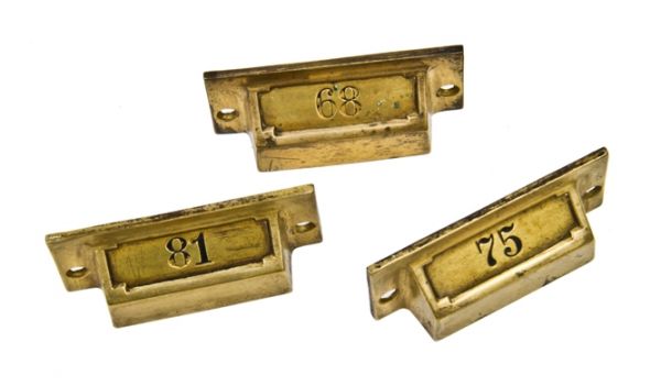 group of three matching early 20th century cast brass drugstore cabinet drawer pulls complete with incised numbers