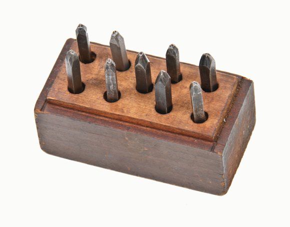group of old american industrial solid steel machine cut hand number stamps with original mahogany wood block base