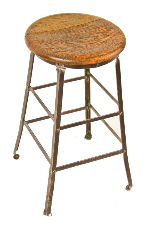 original early 1920's american industrial riveted joint angled steel stationary four-legged stool with inward-turned ball feet and solid oak wood seat