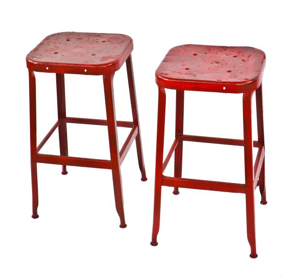two matching c. 1950's vintage industrial red painted pressed and folded steel factory machine shop four-legged stools with perforated seats