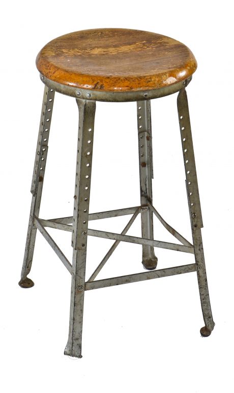 late 1920's all original and intact fully adjustable height maple wood seat four-legged angled steel stationary stool with distinctive inward-turned ball feet for added stabilty