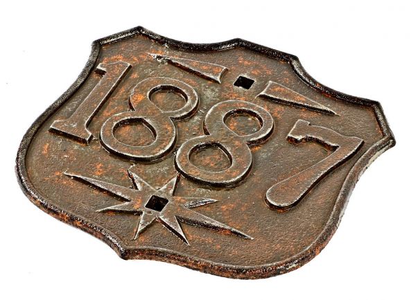 original and intact 1880's antique american ornamental cast iron bridge truss date plaque in the form of a shield with design motifs surrounding the mounting holes