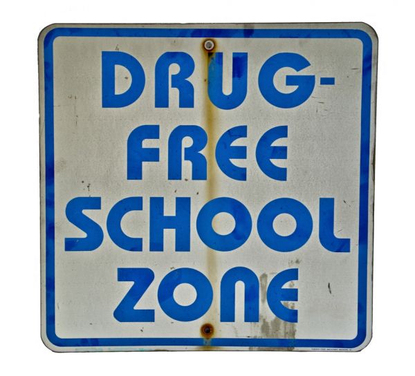 single-sided stamped aluminum "drug free school zone" milwaukee street sign with bold blue lettering containing a reflective finish 