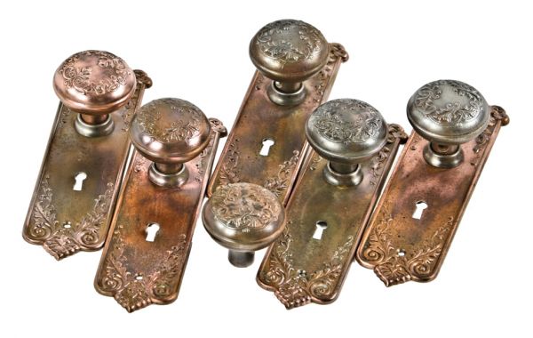 group of original early 20th century antique american interior residential copper-plated stamped steel "loriane" pattern banded rim doorknobs with matching backplates or escutcheons 
