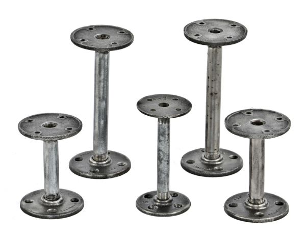 group of repurposed industrial stationary brushed steel display stands or risers comprised of "new old stock" threaded pipe and flanges
