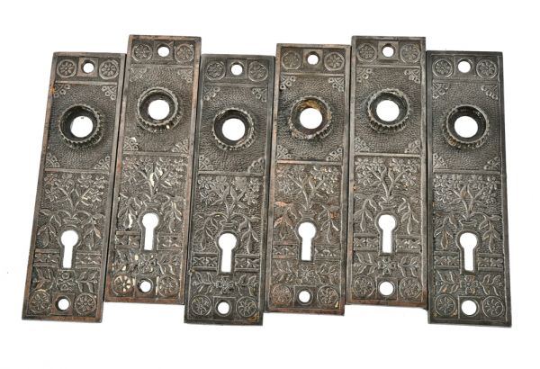 group of matching ornamental cast iron residential antique american victorian era doorknob backplates or escutcheons with brushed metal finish 