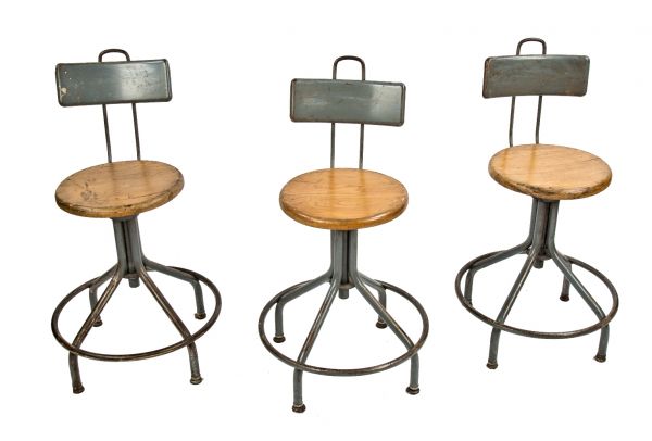 group of three fully adjustable all original salvaged chicago school laboratory stools with solid circular-shaped maple wood seats and welded joint heel rings 