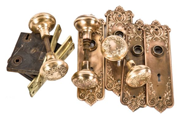group of matching antique american ornamental wrought bronze "loriane" pattern salvaged chicago door hardware with backplates, doorknobs, and mortise locks