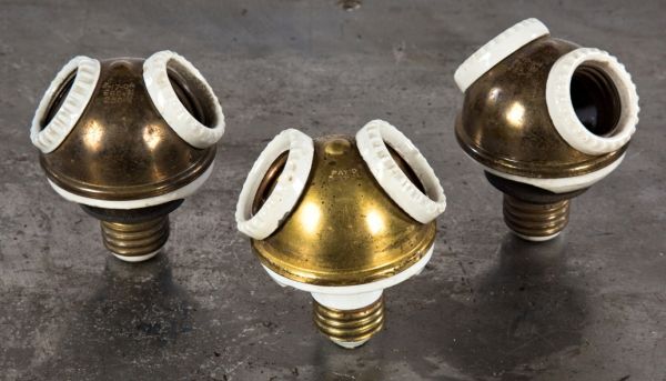 group of three matching early 20th century signal or bryant antique american industrial brass and ceramic double light socket plug clusters with edison screw base plugs