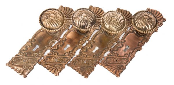 four matching late 19th or early 20th century ornamental wrought brass interior residential passage door backplates and doorknobs in the "roanoke" pattern  